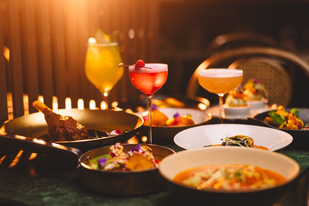 Et bord med ulike matretter og cocktails, med dempet belysning